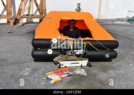 Man inside inflated life raft on land Stock Photo