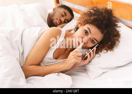 Cheating black woman talking privately on cellphone Stock Photo