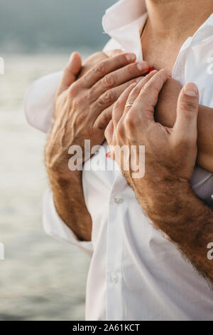 A woman hugs a man and he holds her hands in his hands. Loving couple together. Trust and close relations between people. Stock Photo