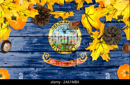 State of Idaho flag on autumn wooden background with leaves and good place for your text Stock Photo