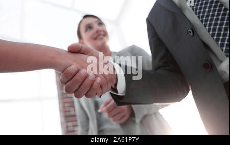 Businesspeople shaking hands against room with large window loo Stock Photo