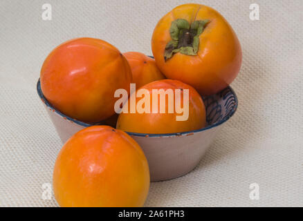 ripe persimmons on a rustic plate Stock Photo