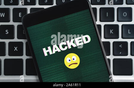 Smartphone with hacked inscription and sad emoji icon on screen Stock Photo