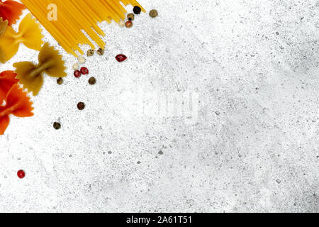 Types of uncooked pasta. Pasta farfalle, spaghetti and colorful peas dry on a light concrete background. Shooting from above. Flat lay, top view, copy Stock Photo