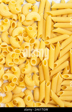 Types of uncooked pasta. Dry penne pasta and chifferi fill the frame. Flat lay, top view, filled frame. Stock Photo