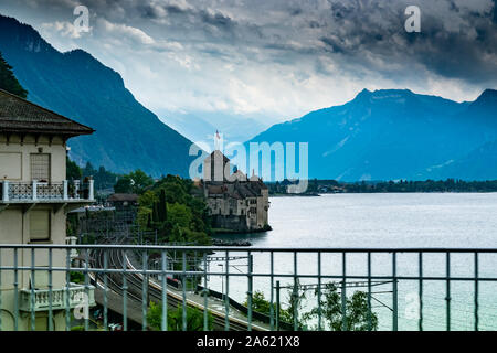 View of the medieval Chillon castle in the canton of Vaud in Switzerland.Lake of geneva and view of Alps mountains,photo from a moving car. Stock Photo