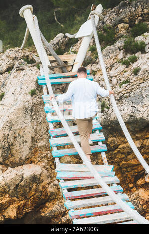 man walking by suspension bridge cross sea bay Stock Photo - Alamy