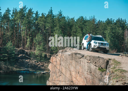 young man at edge with beautiful view of lake near white suv car Stock Photo