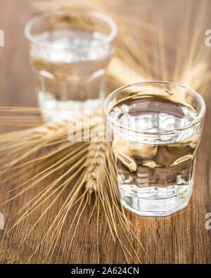 two glasses with corn schnapps and grain together on wooden background Stock Photo