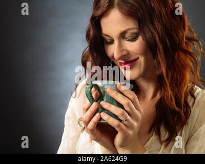 Beautiful happy redhead woman drinking coffee and relaxing. Stock Photo