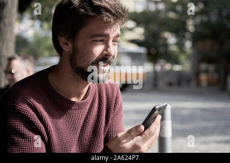 Attractive young bearded man using his smartphone in the cafe Stock Photo