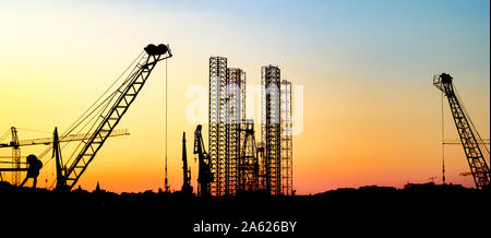 silhouettes of harbor cranes in the port of Valletta city against the evening sky in Malta Stock Photo