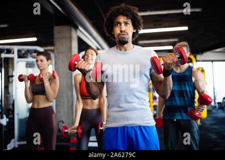 Healthy young people doing exercises at fitness studio. Stock Photo