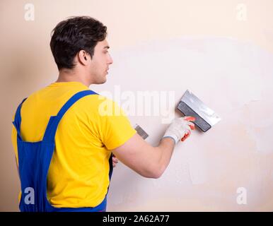 The young contractor employee applying plaster on wall Stock Photo