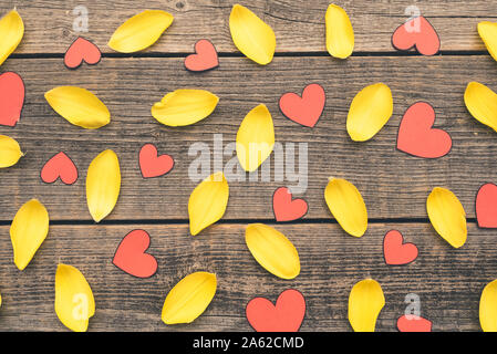 Background composition arranged with yellow tulip petals and red paper hearts. Nice frame with wooden, old boards. Stock Photo