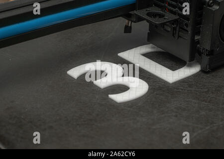 3D printer prints the word 3D with white filament PLA Stock Photo