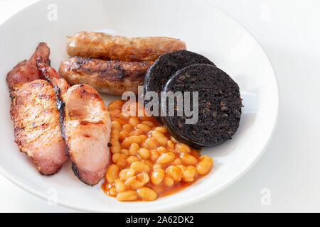 Cumberland sausages, back bacon, baked beans and black pudding in a white bowl Stock Photo