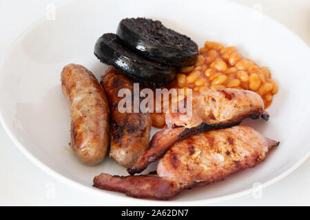 Cumberland sausages, back bacon, baked beans and black pudding in a white bowl