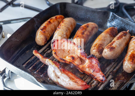 Cumberland sausages and back bacon cooking in a griddle pan Stock Photo