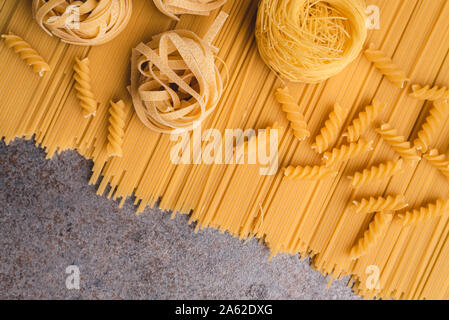 Raw spaghetti pasta and tagliatelle arranged flat with top view. A simple take on the various types of pasta that we can use when cooking. Copy space. Stock Photo