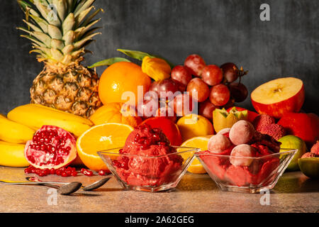 Forest fruit ice cream with a juicy red color, in transparent bowls, sprinkled with pomegranate and grape. The background slightly blurred Stock Photo