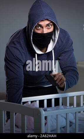 The criminal stealing baby in human child traficking concept Stock Photo