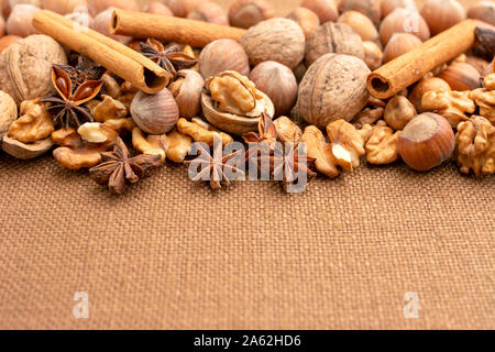 Winter holidays, additions to the cake and warming tea like cinnamon, anise, hazelnuts, walnuts. In shell and without shells. Copy space. Stock Photo