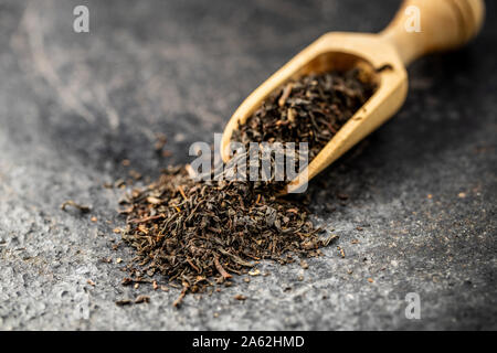 Dried black tea leaves in wooden scoop. Stock Photo