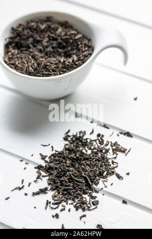 Dried black tea leaves on white table. Stock Photo
