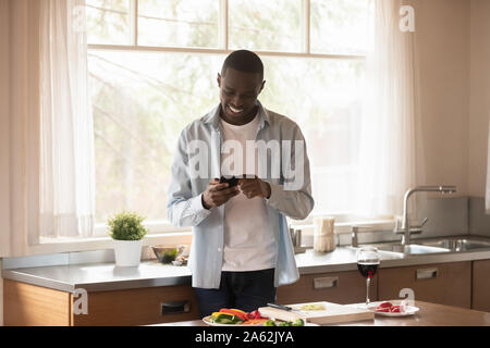 Happy african american man preparing romantic dinner for beloved woman. Stock Photo