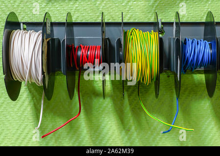 multi colored electrical wires wrapped in reels in a stand on the wall at store Stock Photo