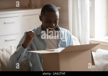 Excited african ethnicity smiling guy satisfied with fast easy delivery. Stock Photo