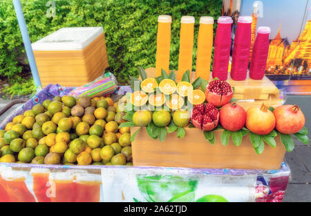 Oranges and pomegranates and fresh juice from these fruits put up for sale on a street in Bangkok. Stock Photo