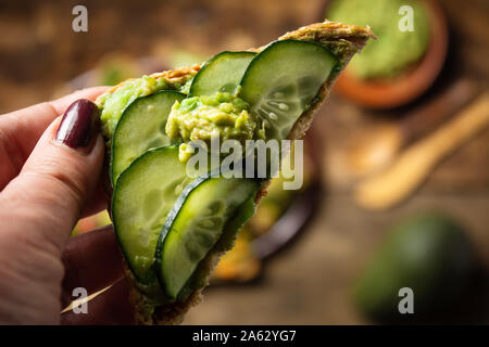 Hand holding avocado and vegetables sandwich first person Stock Photo