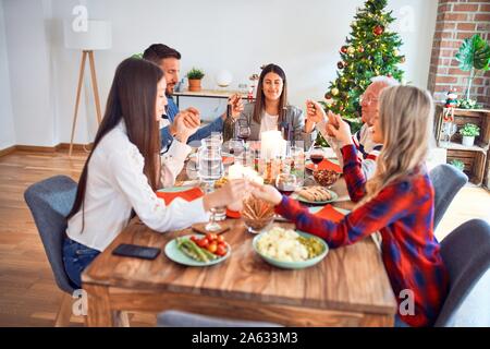 Beautiful family meeting smiling happy and confident. Praying taking hands before eating roasted turkey celebrating Christmas at home Stock Photo