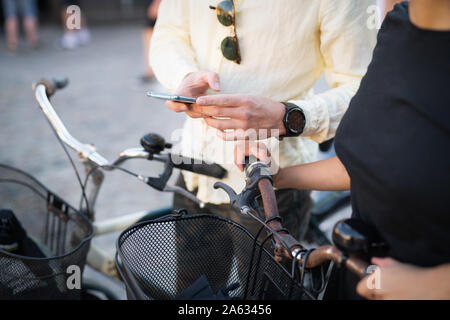 Man showing woman cell phone while biking in town Stock Photo