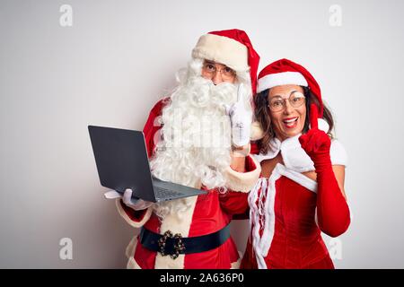 Senior couple wearing Santa Claus costume using laptop over isolated white background surprised with an idea or question pointing finger with happy fa Stock Photo