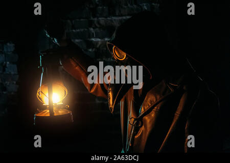 Terrible plague doctor with kerosene lamp. Masked maniac. Halloween and horror concept. Stock Photo