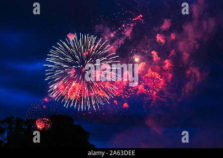 Inexpensive fireworks over the city red, pink and white. Bright and shiny. For any purpose. Celebration concept.