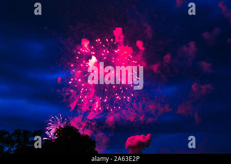 Inexpensive fireworks over the city red, pink and white. Bright and shiny. For any purpose. Celebration concept. Stock Photo