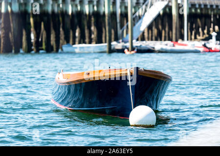 A blue row boat is moored in rough water in Bar Harbor Maine with a peir in the background, Stock Photo