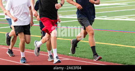 Five high school boys running fast in a group on a red track during cross country practice. Stock Photo