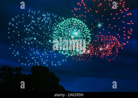 Inexpensive fireworks over the city red, green and yellow on the blue sky. Bright and shiny. For any purpose. Celebration concept.