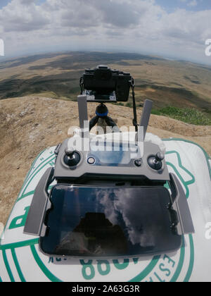 Drone remote controller with phone as monitor and camera on tripod in mountains Stock Photo