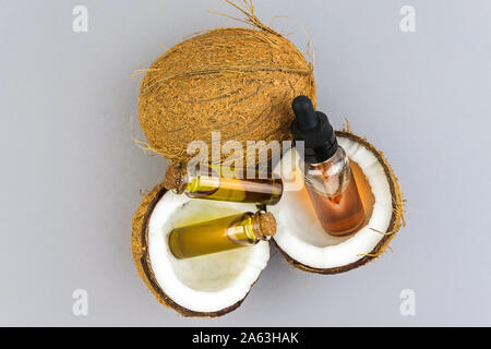 Top view of Half cut coconuts with Coconut essential oils in glass bottles isolated on light grey background Stock Photo