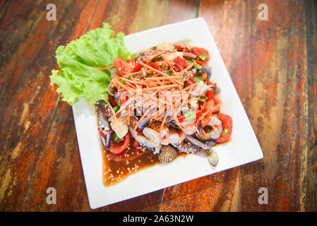 Seafood salad spicy with fresh shrimp crab cockles served on white plate fresh vegetables herbs and spices ingredients with carrot salad lettuce - Som Stock Photo