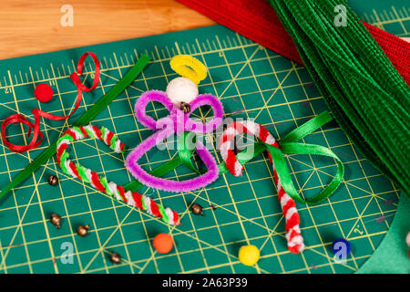 Holiday pipe cleaner crafts. A tight framed Angel and Candy Canes made of pipe cleaners, with additional supplies scattered around the finished crafts Stock Photo