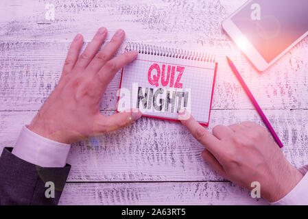 Text sign showing Quiz Night. Business photo text evening test knowledge competition between individuals Hand hold note paper near writing equipment a Stock Photo