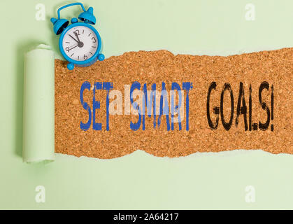 Word writing text Set Smart Goals. Business photo showcasing list to clarify your ideas focus efforts use time wisely Alarm clock and torn cardboard p Stock Photo