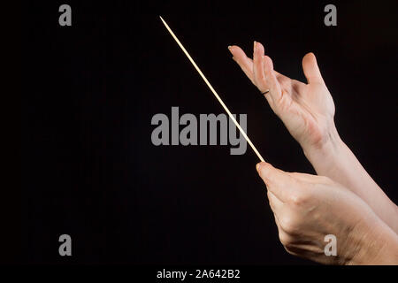Female hands of an orchestra conductor on a black background Stock Photo